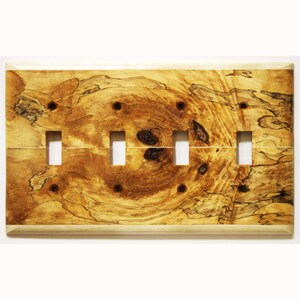 Könnte beinhalten: Eine Holz-Lichtschalterplatte mit vier Schalteröffnungen. Die Platte hat ein natürliches Holzmaserungsmuster mit Braun- und Beigetönen. Sie hat einen hellfarbigen Rand und ist für vier Schalter konzipiert.