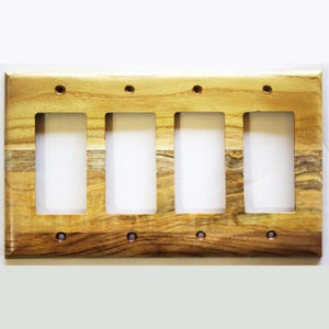 May include: A rectangular light brown wooden wall plate with a natural wood grain pattern. This cover features four vertical rectangular cutouts for switches and eight small circular holes for mounting screws, arranged along the top and bottom edges.