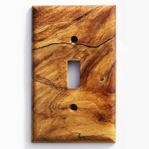 Könnte beinhalten: Rechteckige Lichtschalterabdeckung aus Holz. Die Abdeckung hat eine Öffnung für einen einzelnen Kippschalter und zwei Schraubenlöcher. Das Holzmaserungsmuster ist eine Mischung aus hell- und dunkelbraun mit schwarzen Linien.