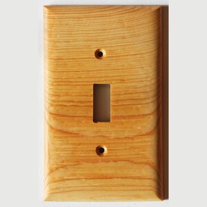 May include: A light wood single switch plate cover with a rectangular cutout for the switch and two round holes for screws.