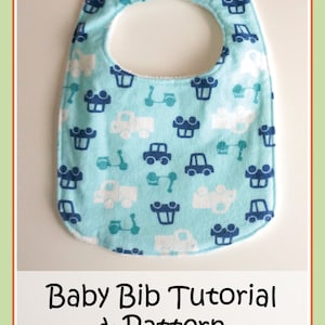 May include: A light blue baby bib with a white and blue car and scooter pattern. The bib has a white trim and a neck opening. The text "Baby Bib Tutorial & Pattern" and "ollie & annie collection" is printed below the bib.
