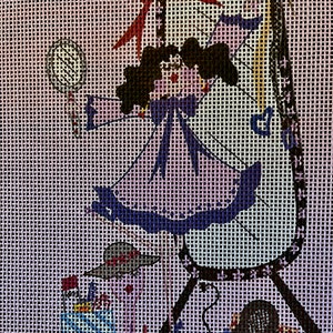 May include: A purple and blue dress with a red bow and a black haired doll holding a mirror in front of a black and white mirror with a stand. The doll is wearing a blue bow around her neck. There are other accessories on the floor, including a hat, a purse, and a pair of shoes.