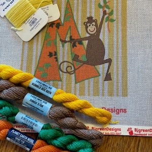 Może przedstawiać: Zbliżenie na nici do haftu w różnych kolorach, w tym pomarańczowym, zielonym, brązowym i żółtym. Nici są ułożone w półkole na drewnianej powierzchni. Nici są oznaczone nazwą marki "Planet Earth Wool" i nazwą koloru "Heat 118".