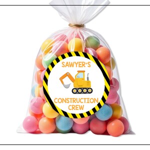 May include: A clear cellophane bag filled with colorful gumballs, tied with twine. A round sticker on the bag features a yellow construction vehicle and the text "SAWYER'S CONSTRUCTION CREW" in a black and yellow border.