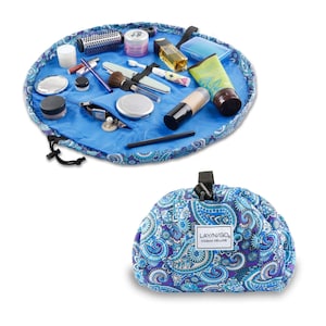 May include: A blue and purple paisley patterned makeup bag with a drawstring closure. The bag is open and laid flat, revealing a variety of makeup and beauty products. The bag is labeled "Layn/Go Cosmo Deluxe".
