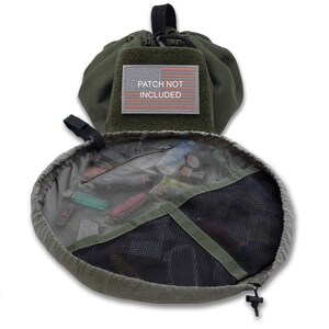 May include: A green drawstring pouch with a mesh interior and a zippered pocket. The pouch is open and filled with various items, including a lighter, a knife, and a small flashlight. The pouch has a patch on the front that says "PATCH NOT INCLUDED".