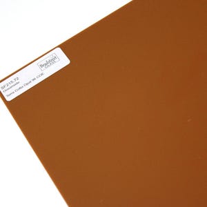 May include: A flat sheet of opaque terra cotta colored glass. A white rectangular label is affixed to the surface, printed with the text Bradstreet Glass, SF215.72, Oceanside, and Terra Cotta Opal 96 COE.
