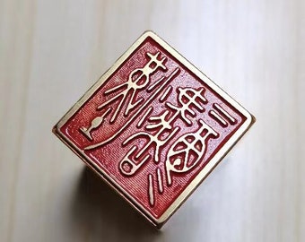 May include: A red square-shaped stamp with gold lettering. The lettering is in Chinese characters.