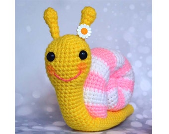 May include: A crocheted snail toy with a yellow body and pink and white striped shell. The snail has a small white flower on its head and black eyes.