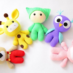 May include: Five crocheted stuffed animals in a circle on a white background. The animals are a yellow giraffe, a green person, a purple owl, a brown bear wearing red overalls, and a pink bear.