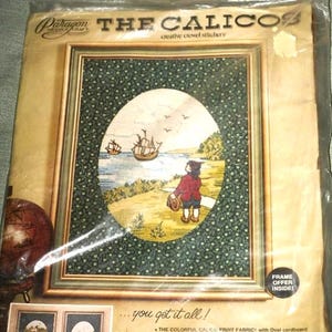 May include: A vintage "The Calico" creative crewel stitchery kit. The kit features an oval-shaped design with a boy on a hill, ships on the water, and a green patterned border. The kit includes fabric, yarn, and instructions. The frame is not included.