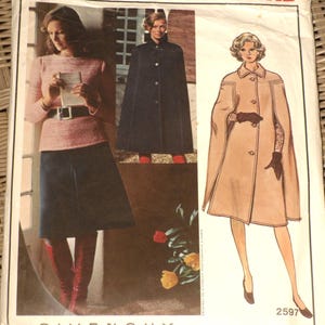 May include: Vintage Vogue Paris Original sewing pattern for a cape coat by Givenchy. The pattern number is 2597. The pattern shows two models wearing the cape coat in different colors.