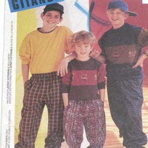 May include: Image of a vintage McCall's sewing pattern featuring three children in colorful outfits. The pattern is labeled "GITANO" and includes instructions for tops and pants. The children are wearing a yellow shirt, a maroon and red striped sweater, and a navy blue and brown sweater.