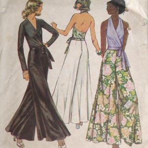 May include: Vintage sewing pattern featuring three women in stylish jumpsuits. The designs include a black jumpsuit with a wrap tie, a white jumpsuit with a floral halter top, and a floral print jumpsuit with a lavender wrap top. The pattern is size 12, with a 34-inch bust and a 26.5-inch waist.