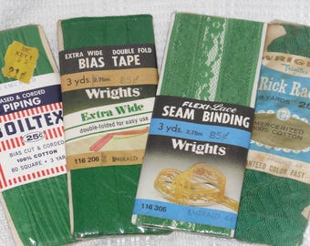 May include: An assortment of vintage green sewing trims, including bias tape, seam binding, and rick rack. The packages feature text labels with product information and branding, such as "Wrights" and "Boiltex".