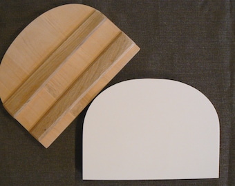 May include: Two semi-circular objects on a dark background. One is made of light-colored wood with darker wood strips, the other is a plain white shape. The wooden object has a curved edge and a flat edge.