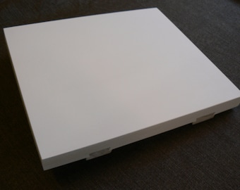 May include: A square, white wooden shelf with a smooth, matte finish. The shelf has a simple, minimalist design and is likely intended for display or storage purposes. The edges are clean and the corners are squared.
