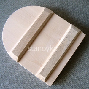May include: A wooden dough scraper with a rounded top and two wooden strips on the surface. The scraper is made of light wood and has a natural finish.