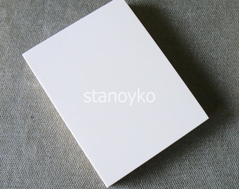 May include: A blank white card on a textured gray surface.