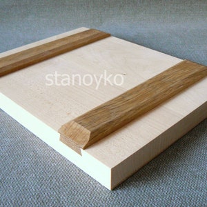 May include: A light wood panel with two strips of darker wood attached to the top and bottom. The wood panel is smooth and has a natural grain.