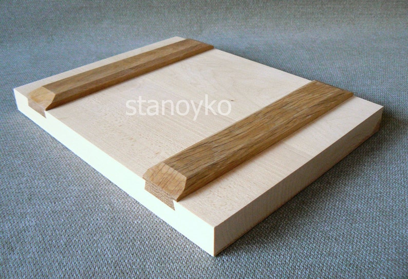May include: A light wood panel with two strips of darker wood attached to the top and bottom. The wood panel is smooth and has a natural grain.