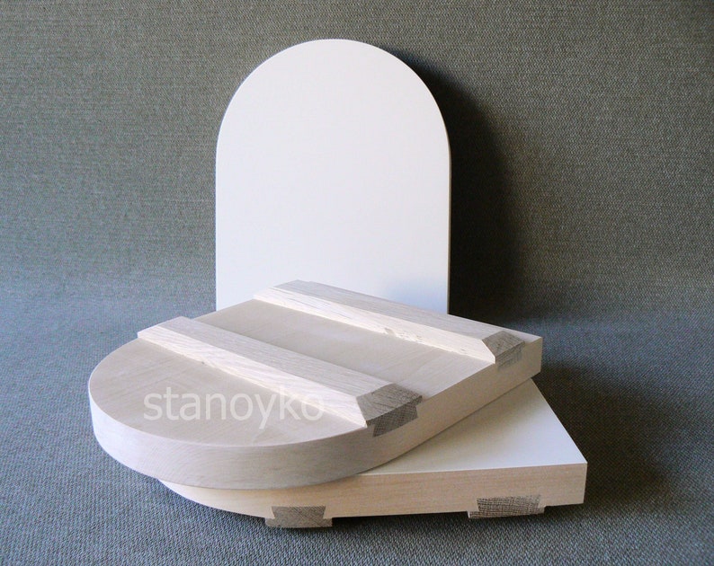 May include: Two wooden bowls, one stacked on top of the other, with a white background behind them. The top bowl is round and has a slightly curved edge. The bottom bowl is rectangular and has a flat edge. Both bowls are made of light-colored wood and have a smooth finish.