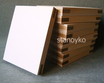 May include: A stack of wooden panels with a white surface on top. The panels are made of light wood with dark wood accents. The panels are stacked in a staggered pattern.