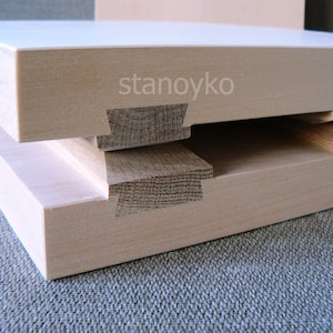 May include: Two pieces of light wood joined together with a dovetail joint. The wood is smooth and has a natural grain. The text "stanoyko" is visible on the top piece of wood.