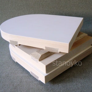 May include: Three wooden panels stacked on top of each other. The top panel is white and has a rounded top edge. The bottom two panels are natural wood color.