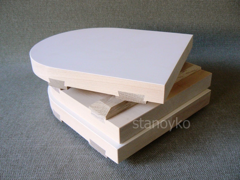 May include: Three wooden panels stacked on top of each other. The top panel is white and has a rounded top edge. The bottom two panels are natural wood color.