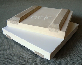 Può includere: Due pannelli di legno, uno sopra l'altro. Il pannello superiore è di colore marrone chiaro con un bordo rialzato e il testo "stanoyko" stampato su di esso. Il pannello inferiore è bianco.