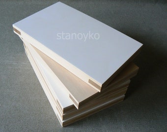 May include: A stack of white painted plywood boards with visible wood edges. The boards are stacked in a staggered pattern, with the top board being the largest.