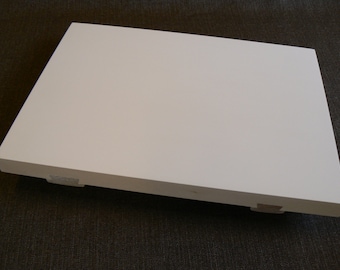 May include: A white rectangular shelf with rounded edges and two small wooden feet on each side.