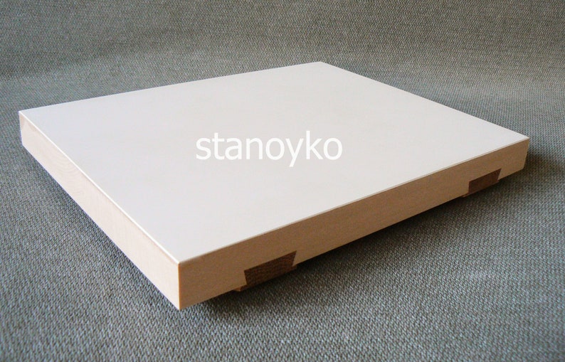 May include: A white rectangular wooden box with a smooth surface and rounded edges. The box is made of light wood and has a white top. The box is sitting on a gray textured surface. The text "stanoyko" is printed on the top of the box.