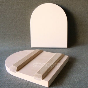 May include: Two wooden panels, one with a rounded top and the other with a flat top, both with a light wood finish. The rounded panel has two wooden supports attached to the back.