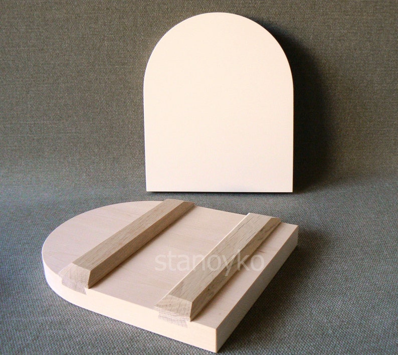 May include: Two wooden panels, one with a rounded top and the other with a flat top, both with a light wood finish. The rounded panel has two wooden supports attached to the back.