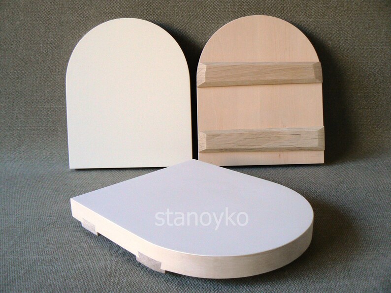 May include: Three wooden arched plaques, two with a white finish and one with a natural wood finish. The plaques have a rounded top and a flat bottom. The natural wood plaque has two horizontal wooden strips across the front. The text "stanoyko" is printed on the bottom of one of the white plaques.