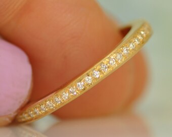 May include: A thin gold band with a row of small diamonds set in the metal.