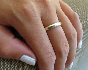 Könnte beinhalten: Ein schlichter goldener Ehering an einem Finger.