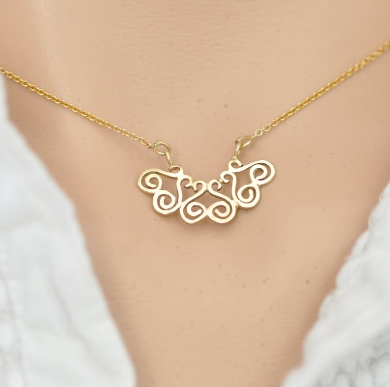 Puede incluir: Un collar de oro con un delicado y complejo colgante que presenta un dise&ntilde;o abstracto en espiral.