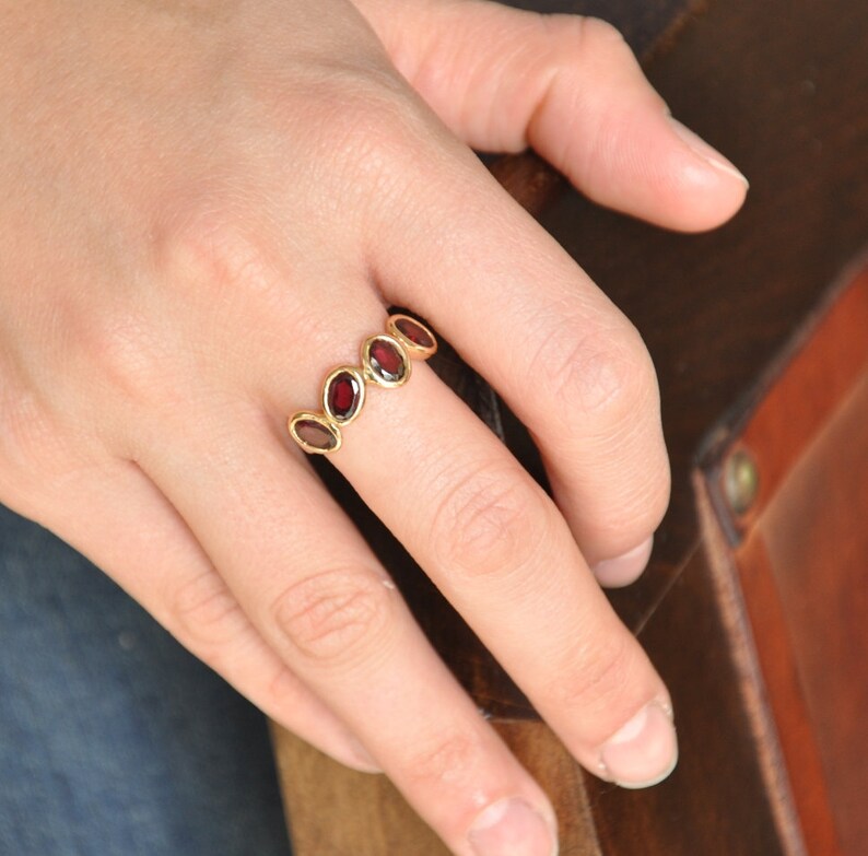 Puede incluir: Un anillo de oro con una banda de piedras preciosas rojas ovaladas.