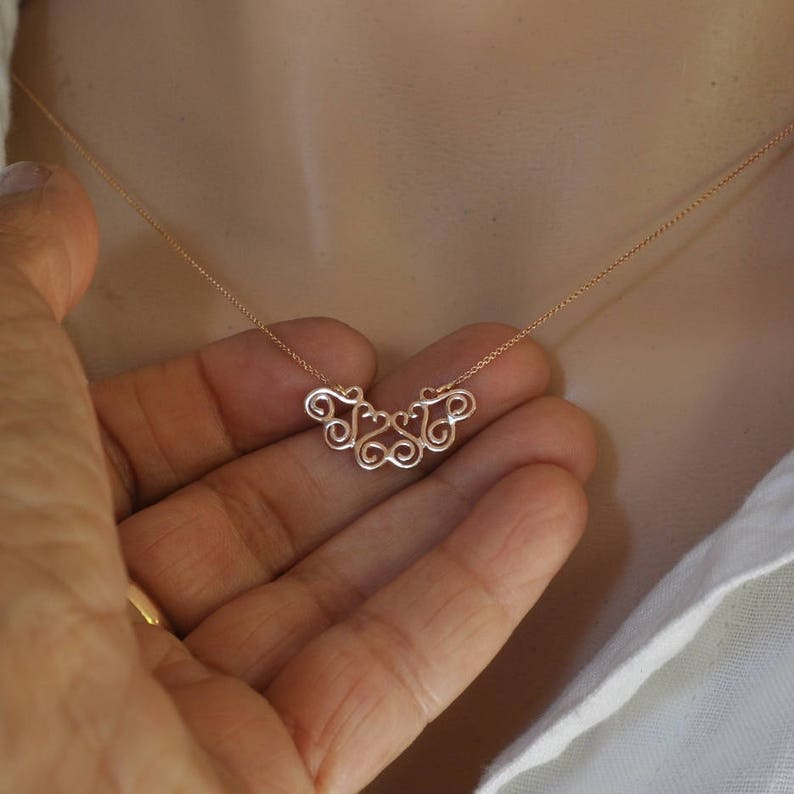 Puede incluir: Un delicado collar de oro con un colgante que presenta un dise&ntilde;o estilizado de c&iacute;rculos entrelazados.