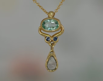 May include: A gold pendant necklace with a light blue oval gemstone, two smaller blue gemstones, and a teardrop-shaped white gemstone.
