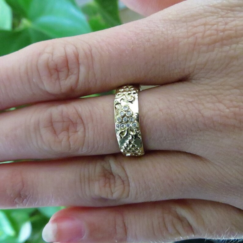 Puede incluir: Un anillo de banda de oro con un dise&ntilde;o texturizado y peque&ntilde;as piedras transparentes engastadas en la banda.
