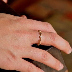May include: A gold ring with a row of small round stones. The stones are a mix of clear and brown.
