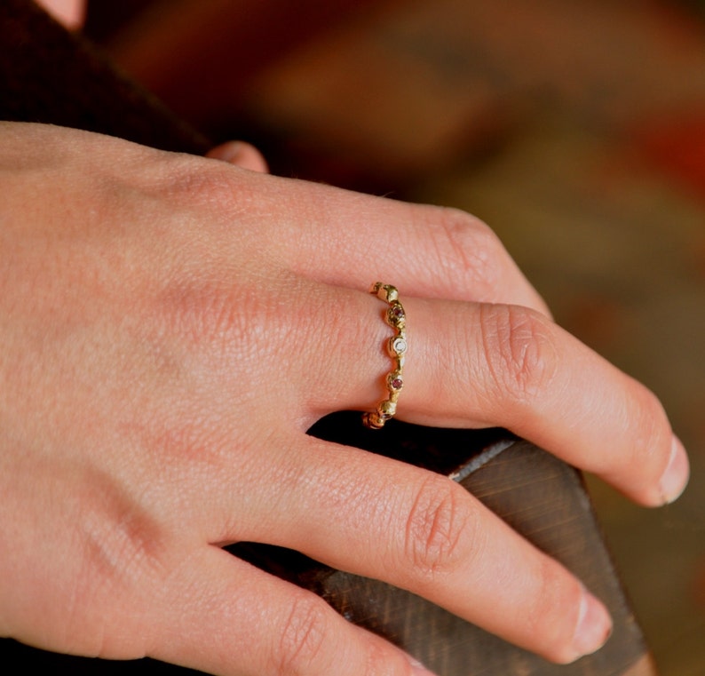 May include: A gold ring with a row of small round stones. The stones are a mix of clear and brown.