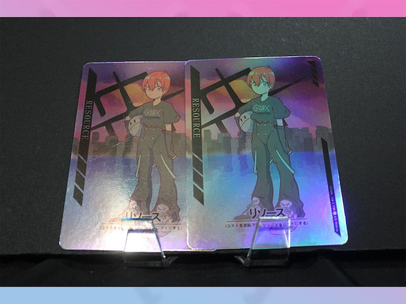 May include: Two holographic trading cards featuring a cartoon character with red hair and a green outfit. The cards have the word "RESOURCE" printed vertically on the left side. The background has a cityscape design.