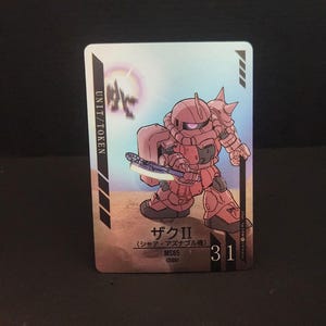 Puede incluir: Taza de cer&aacute;mica blanca con asa negra y la frase "But First, Coffee" en negro. La taza se muestra sobre un fondo borroso, sugiriendo un ambiente acogedor.