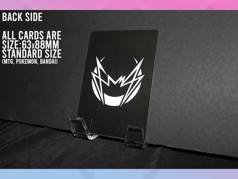 Puede incluir: Una tarjeta negra con un dise&ntilde;o gr&aacute;fico blanco, exhibida en un soporte de pl&aacute;stico transparente. Se ve el reverso de la tarjeta, con texto que indica un tama&ntilde;o de 63x88mm. El texto tambi&eacute;n menciona MTG, Pokemon y Bandai.