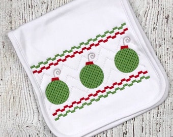 May include: White fabric bib with a green, red, and white embroidered design of three Christmas ornaments.